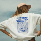 Person wearing a white t-shirt with a blue graphic and text, standing against a cloudy sky.